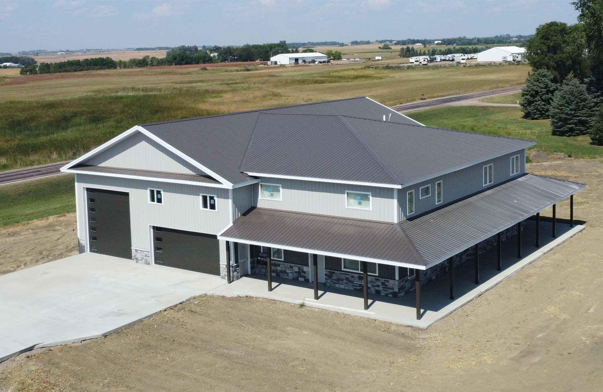 Off-white barndominium with grey roof on a farm and ranch property