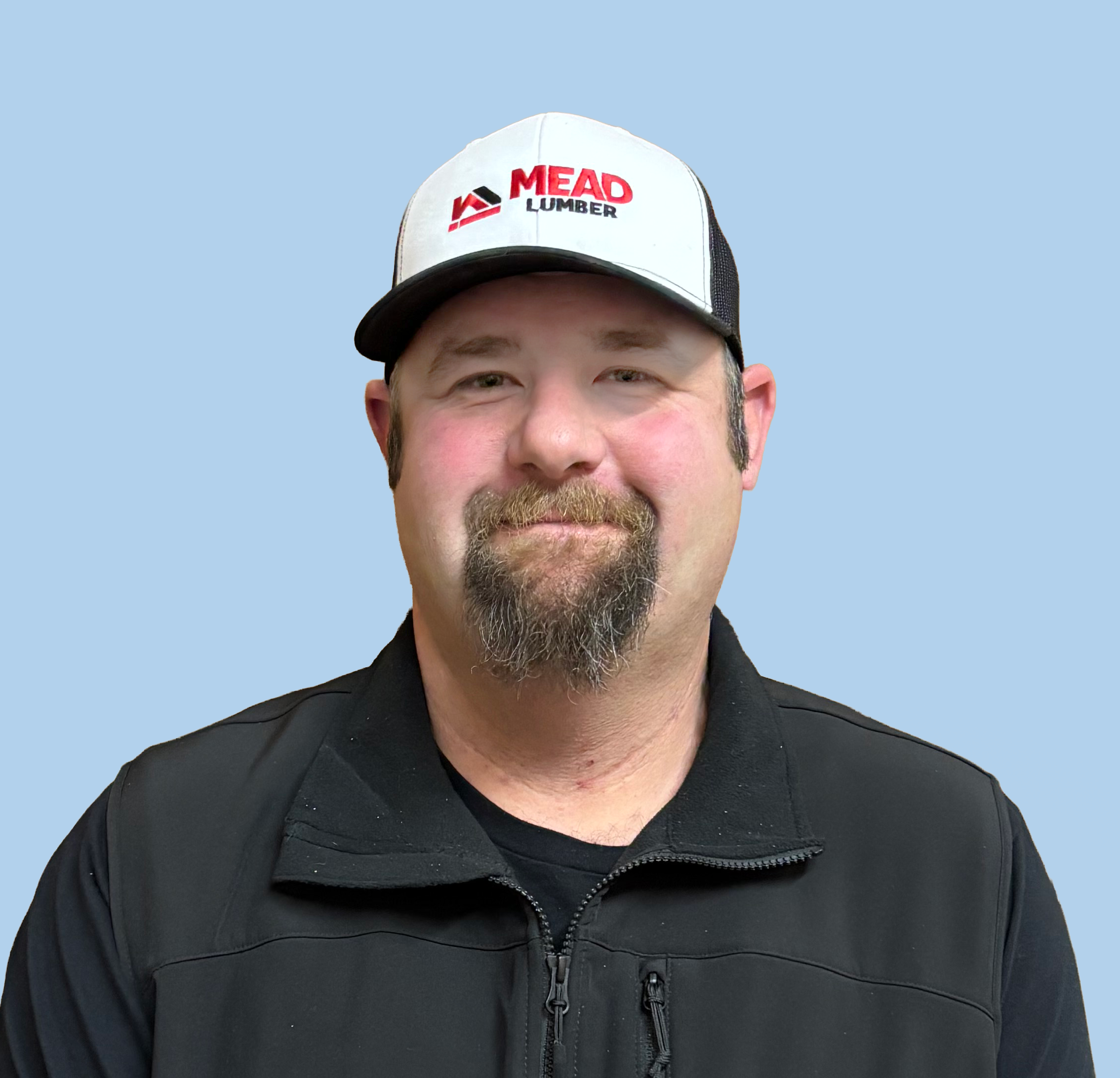 Headshot of Aaron Stark wearing a black zip up shirt and a black and white ballcap with a Mead Lumber logo on the front.