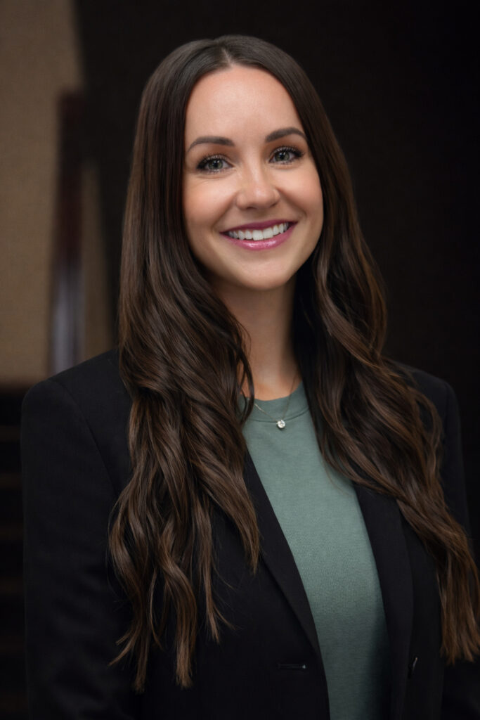 Mead Lumber Joni Konwinski headshot with long dark curled hair, teal shirt and dark blazer.