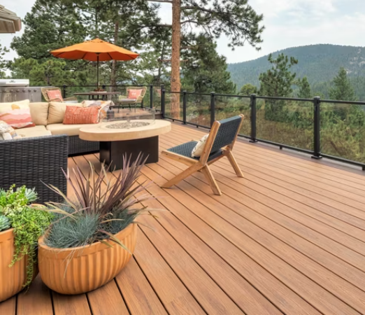 Honey colored composite deck with a black railing, a red sun umbrella, chair, plant, and firepit.